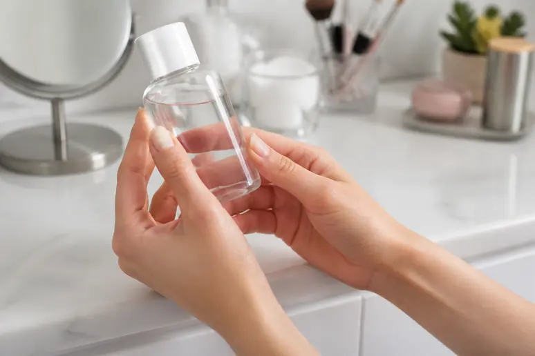 Main tenant une bouteille d'acétone pour comment retirer des faux ongles sans abîmer les ongles naturels.