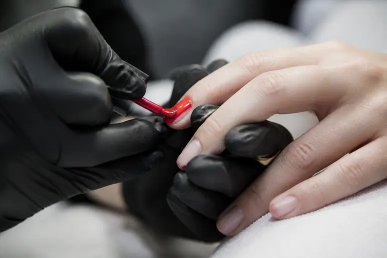 Application minutieuse de vernis semi-permanent pour une meilleure tenue, une professionnelle dévouée.