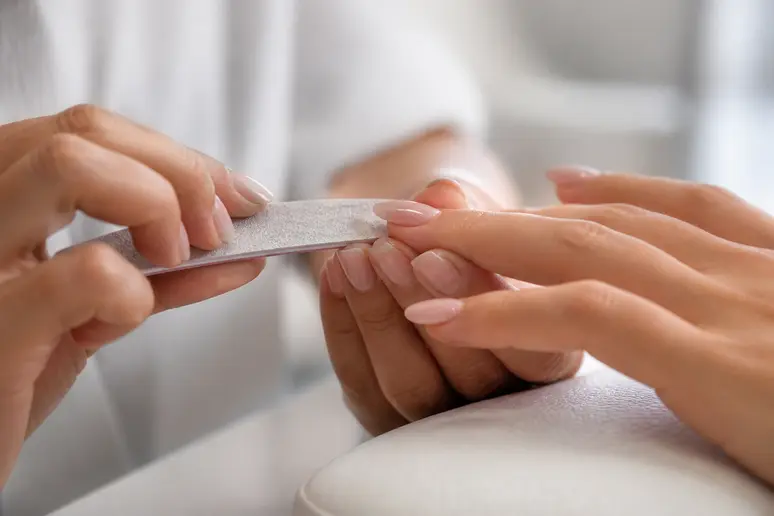 Main d'esthéticienne travaillant sur un ongle en gel, calcul ongle gel prix