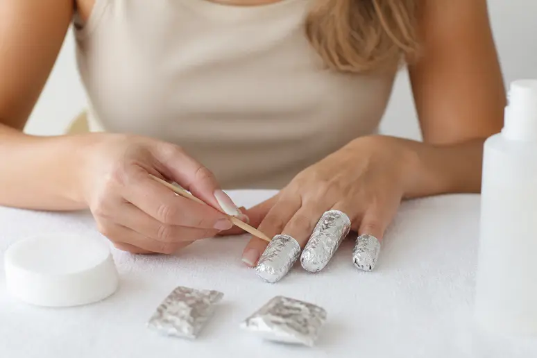 Retrait doux du vernis semi-permanent baby boomer avec une spatule en bois, préservant l'ongle.