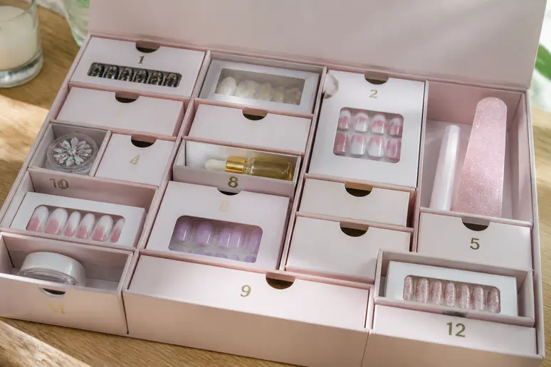 Calendrier de l'Avent manucure ouvert sur une table avec ses petites cases en carton et accessoires