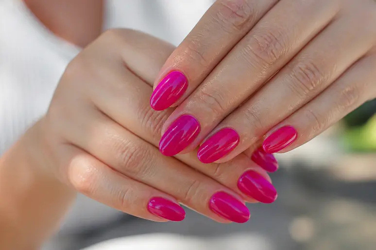 Manucure tendance été avec des ongles couleur fuchsia et un fini vernis Jelly lumineux.