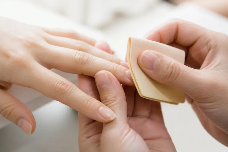 Mains utilisant un polissoir en chamois pour une formation manucure japonaise sur ongle naturel.