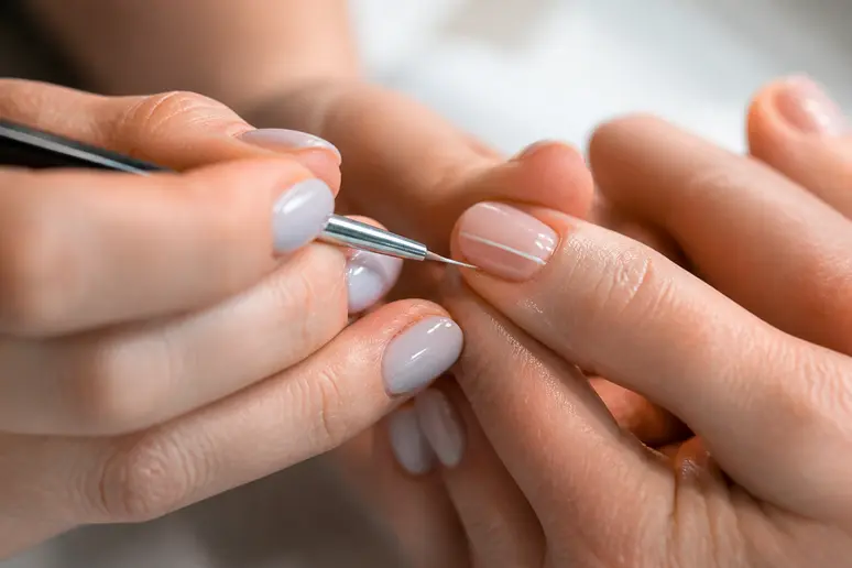 Tracé d'un liseré fin avec un pinceau spécial sur des ongles courts.