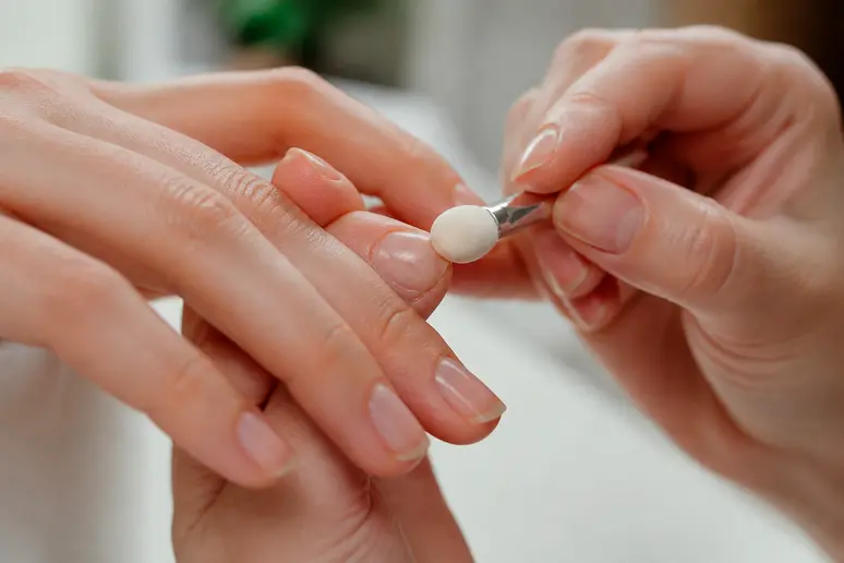 Application délicate d'une poudre de finition nourrissante pour parfaire la manucure chinoise sans surcharger l'ongle.