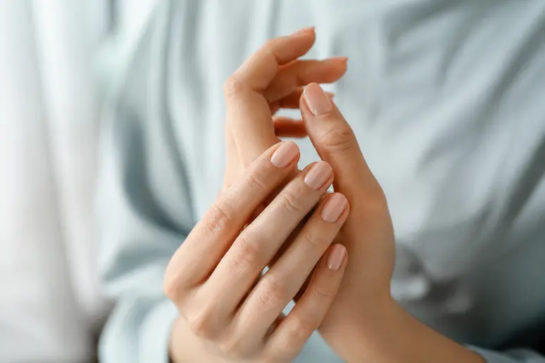 Mains portant une manucure nude discrète et soignée sur des ongles naturels