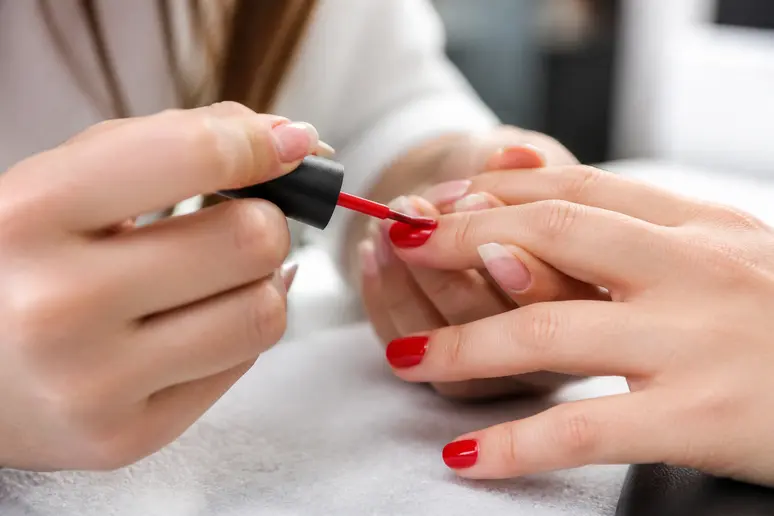 Application d'un vernis rouge éclatant pour une manucure de Noël élégante sur ongles courts