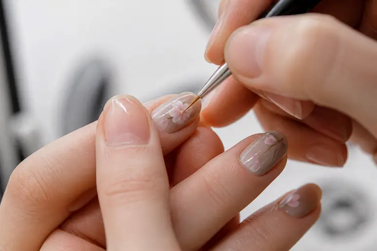Technique de nail art printanier avec un pinceau fin sur une manucure