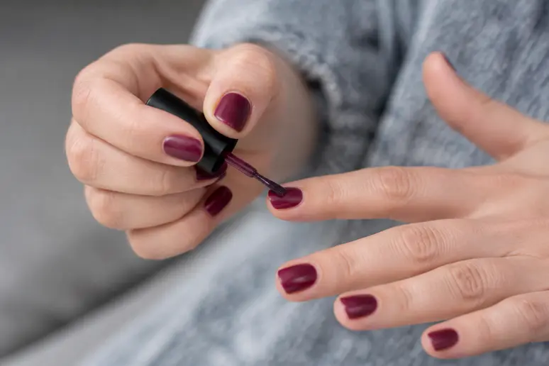 Application au pinceau d'un vernis prune profond sur les ongles