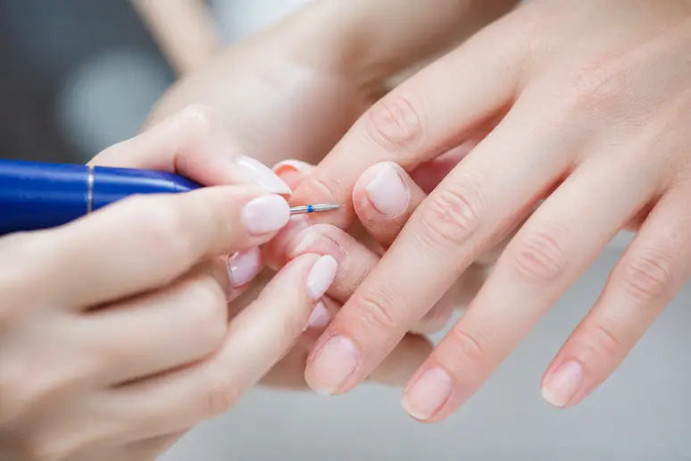 Gros plan sur l'utilisation d'une ponceuse électrique pour une manucure russe sur les ongles