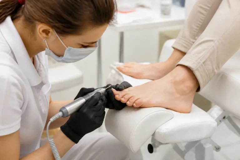 Une esthéticienne effectue une manucure russe pied avec un petit embout ponceur dans un salon lumineux