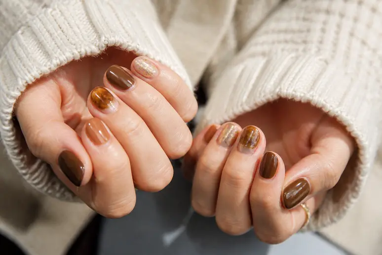 Manucure aux teintes marron et caramel pour un nail art hiver tendance sur ongles courts.