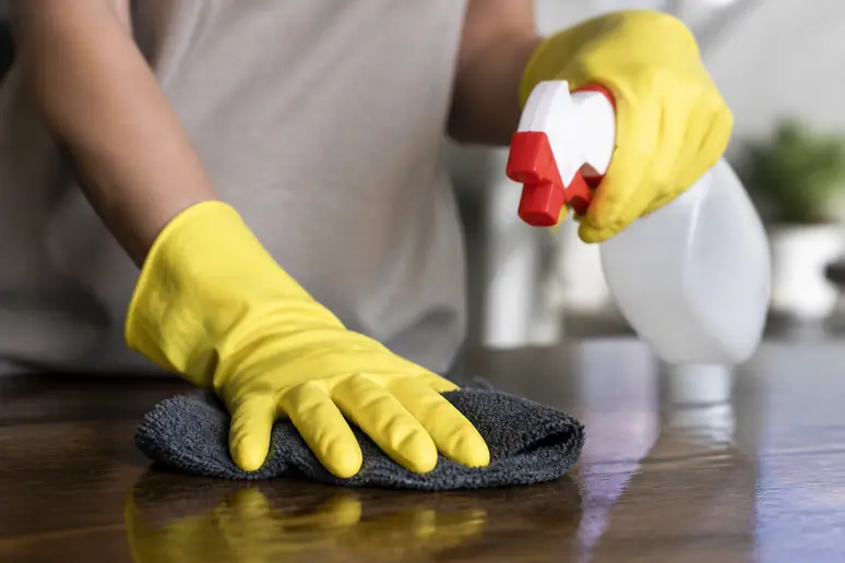 Mains portant des gants en caoutchouc lors de tâches ménagères avec des produits d'entretien