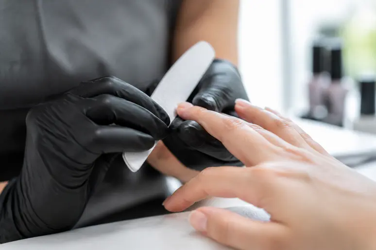 Professionnelle appliquant des soins délicats sur les ongles en gel couleur été.