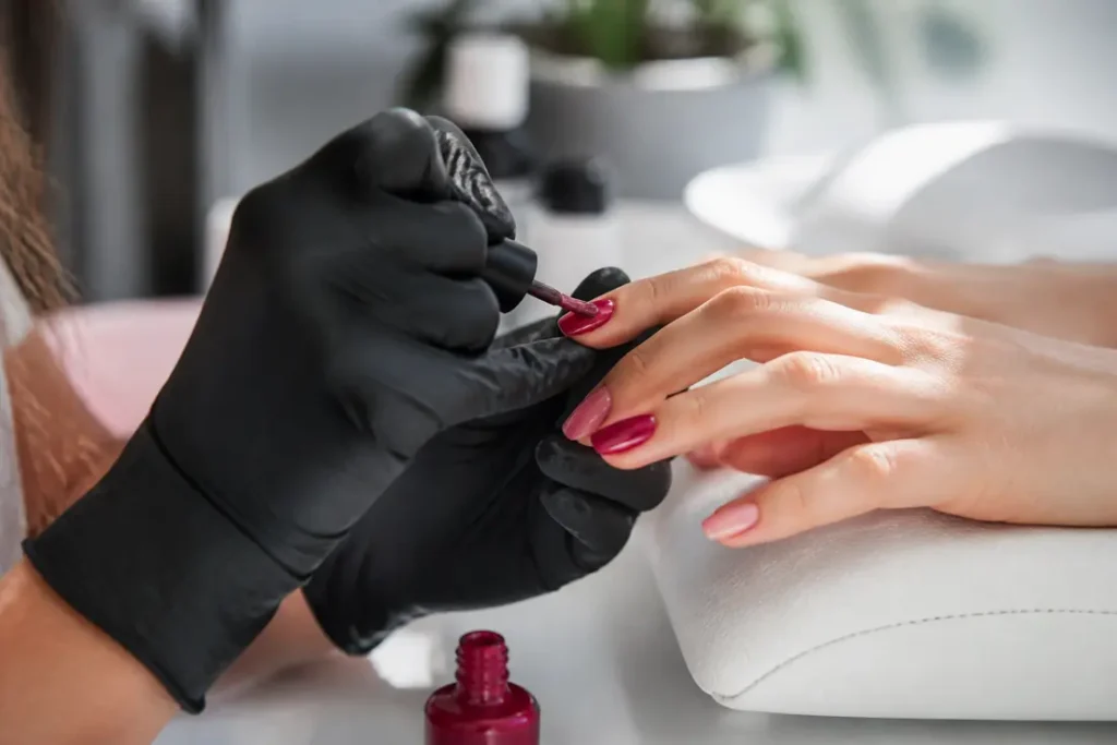 Prix formation onglerie : mains expertes en action, une prothésiste ongulaire applique un vernis