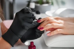 Prix formation onglerie : mains expertes en action, une prothésiste ongulaire applique un vernis