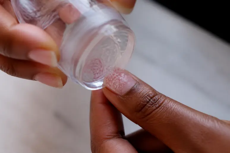 Transfert d'un motif de stamping nail art sur l'ongle par un roulement de tampon.