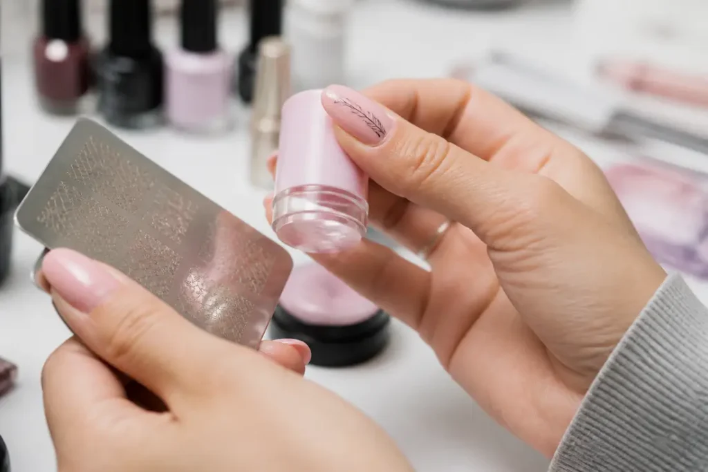 Application méticuleuse de stamping nail art par une femme dans un cadre domestique lumineux et ordonné.