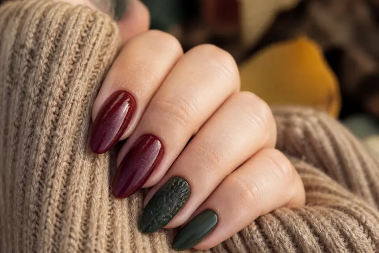 Manucure tendance nail art automne avec des ongles bordeaux et vert sapin profonds et texturés.