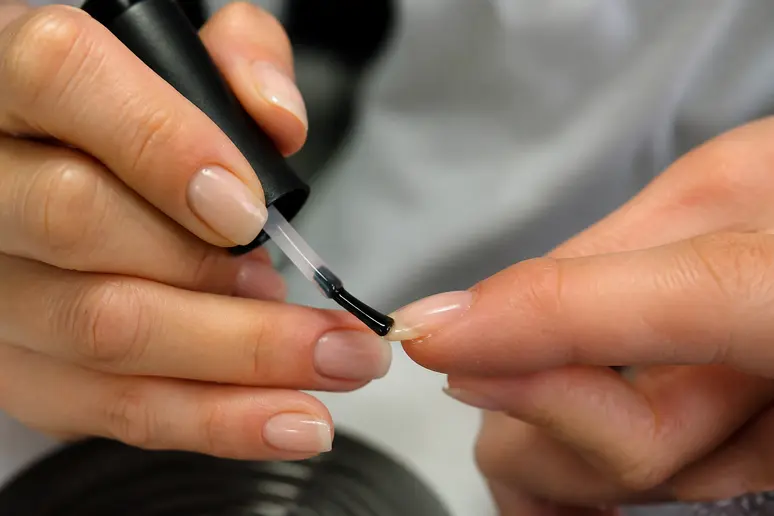 Démonstration précise du capping pour un nail art automne, scellant le bord libre de l'ongle.