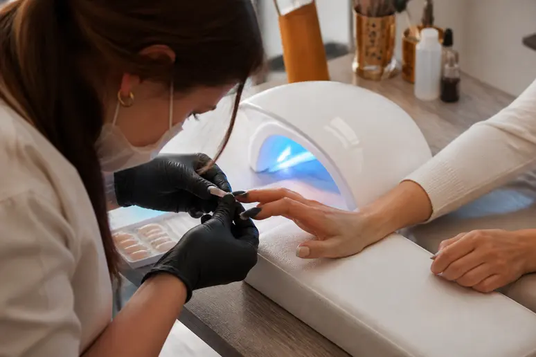 Application d'une capsule nail art en gel souple sous une lampe UV en salon