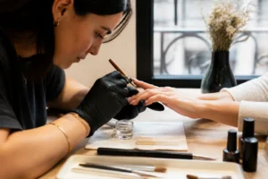 Gros plan sur une manucure réalisant une pose de capsule nail art dans un salon lumineux