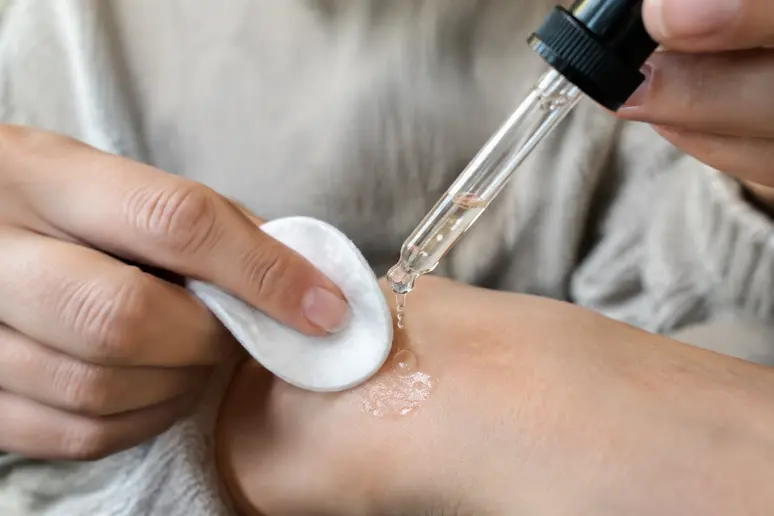 Application délicate d'une huile cosmétique avec un coton doux pour dissoudre les résidus de cire sur la peau.
