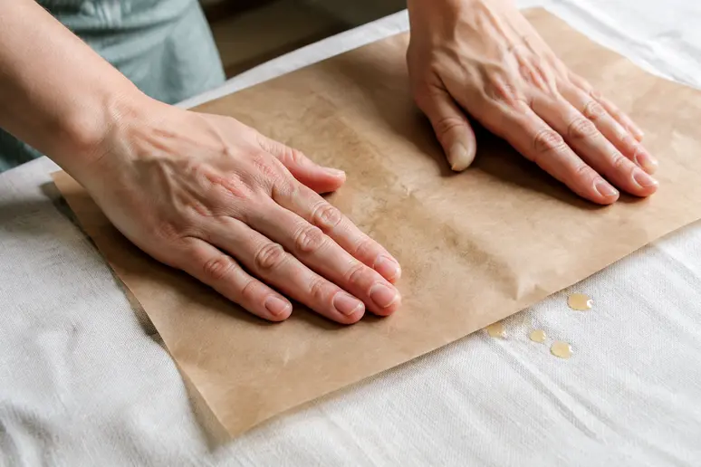 Utilisation d'une feuille de papier absorbant sur un tissu pour décoller la cire durcie.