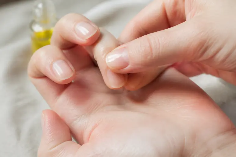 Application d'une huile à cuticules nourrissante par massage circulaire sur la base des ongles