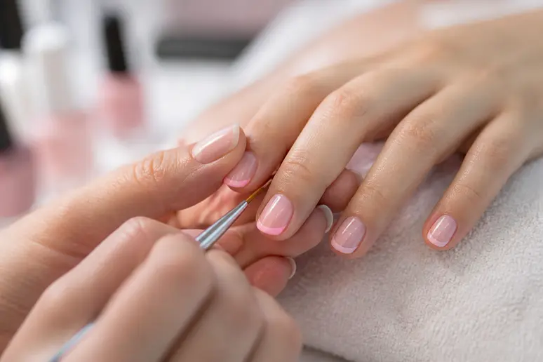 Application d'un liseré pastel très fin sur un ongle court pour une idée nail art printemps réussie