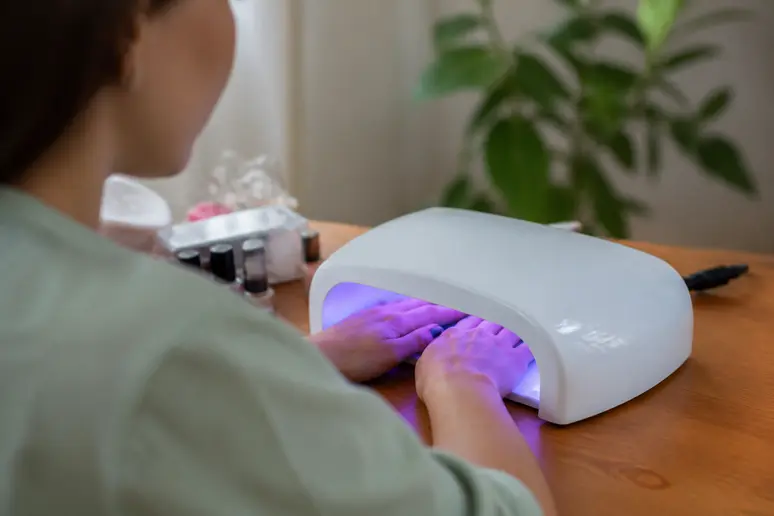 Utilisation d'une lampe UV manucure pour catalyser un vernis semi-permanent à la maison.