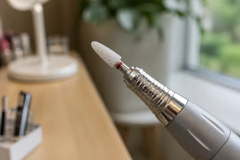 Gros plan sur un embout de ponceuse en céramique posé sur une table de manucure.