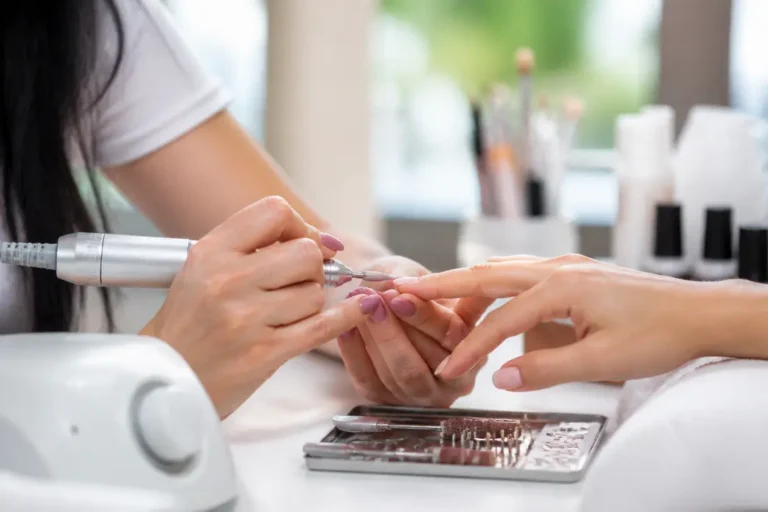 Gros plan sur une utilisation embouts ponceuse ongles à plat lors d'une manucure professionnelle en salon