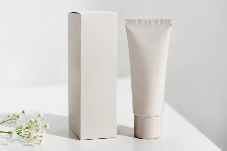 Boîte de produit d'épilation et tube cosmétique posés sur une surface blanche