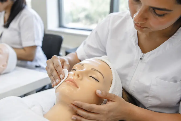 Pratique d'un soin du visage sur une tête d'entraînement en formation d'esthétique
